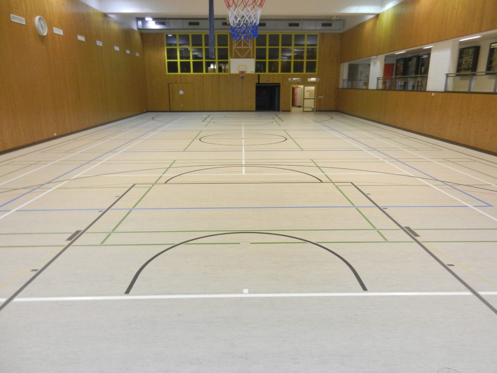 Terrain de basket aux normes FIBA tracé en noir sur un sol sportif en linoléum