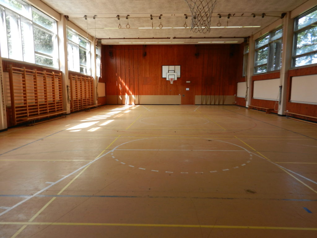 Ancien lino-liège collé sur chape, avec des lignes de jeu usées, dans une salle de sport