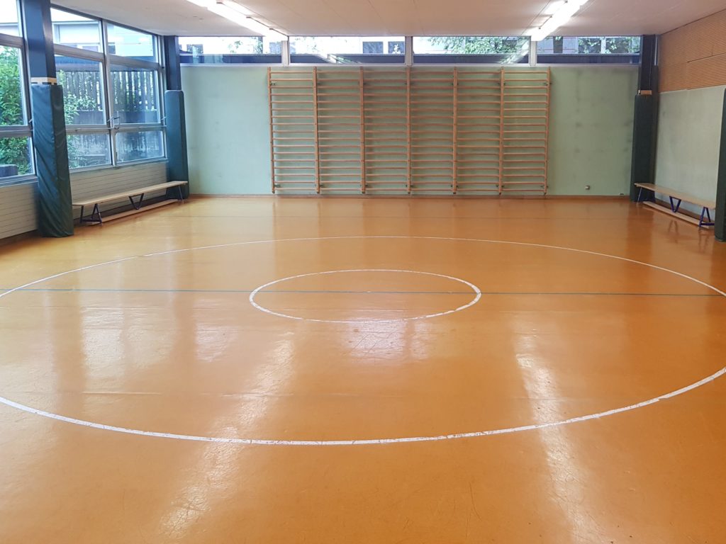 Ancien lino-liège orange usé dans une salle de rythmique scolaire