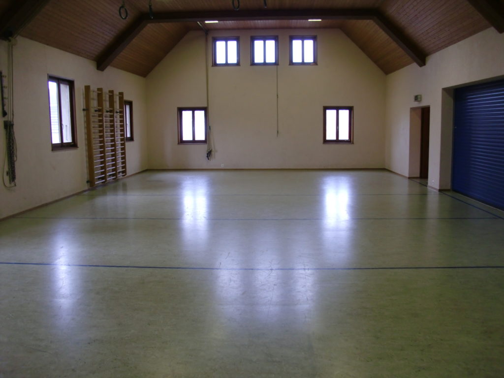 Ancien revêtement terne et rayé dans une salle polyvalente, avant les travaux
