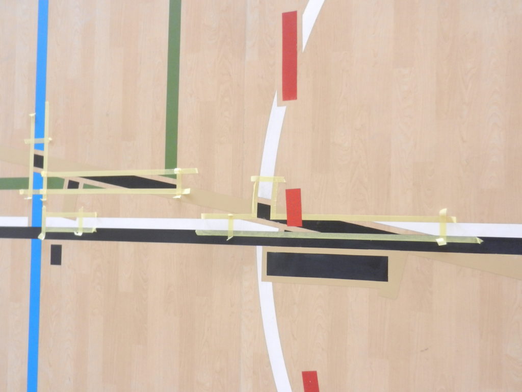 Ancienne ligne de jeu recouverte d'une teinte proche du décor bois, nouvelles lignes de basket protégées au ruban