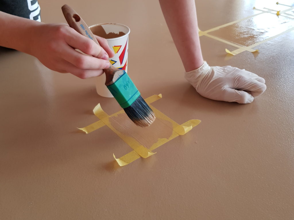 Application au pinceau de résine polyuréthane sur une fissure de sol sportif encadrée de ruban de masquage