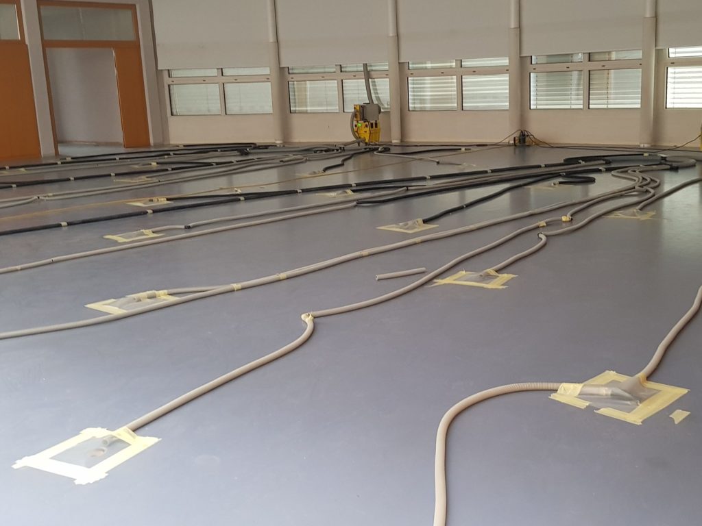 Salle de sport en cours d'assèchement, gaines raccordées aux carottages du sol et déshumidificateurs le long des fenêtres