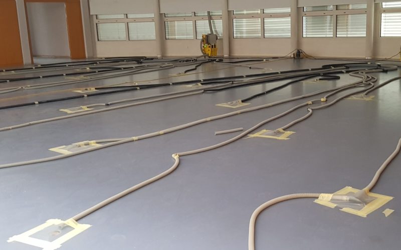 Salle de sport en cours d'assèchement, gaines raccordées aux carottages du sol et déshumidificateurs le long des fenêtres
