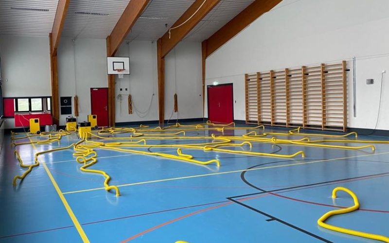 Salle de sport pendant l'assèchement du sol, gaines jaunes réparties sur la surface de jeu et reliées aux déshumidificateurs