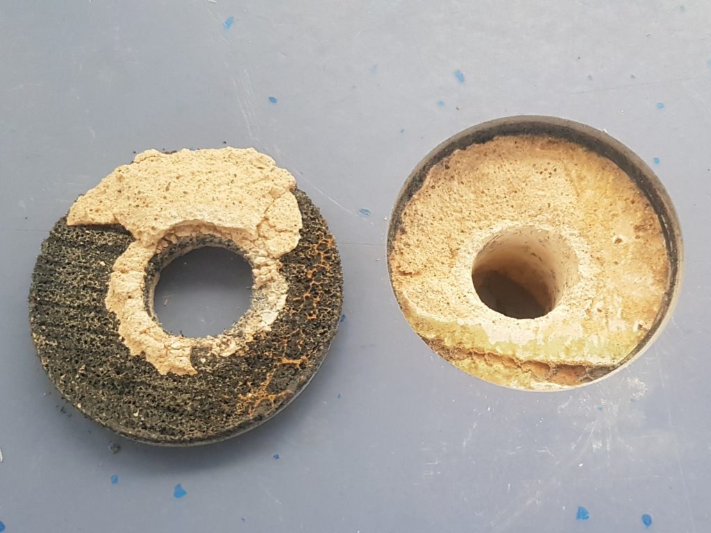 Carotte extraite d'un sol sportif après une rupture de conduite, sous-couche et chape marquées par l'humidité, à côté du trou de carottage