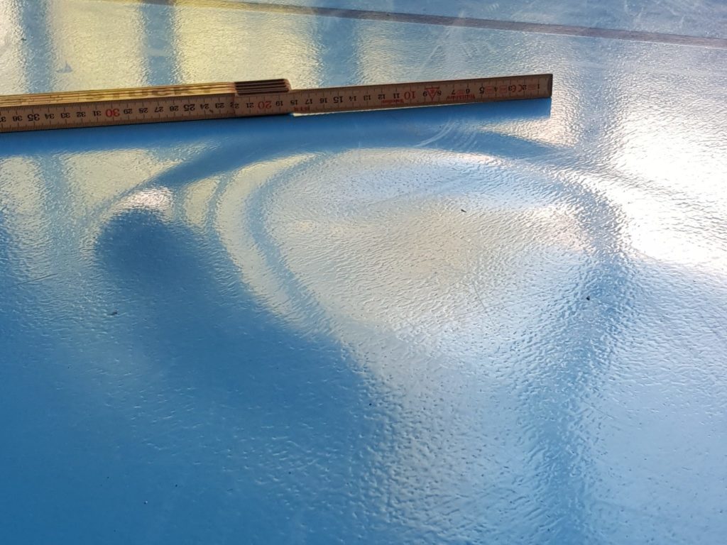 Mètre pliant posé sur un sol sportif pour montrer le soulèvement du revêtement par une cloque