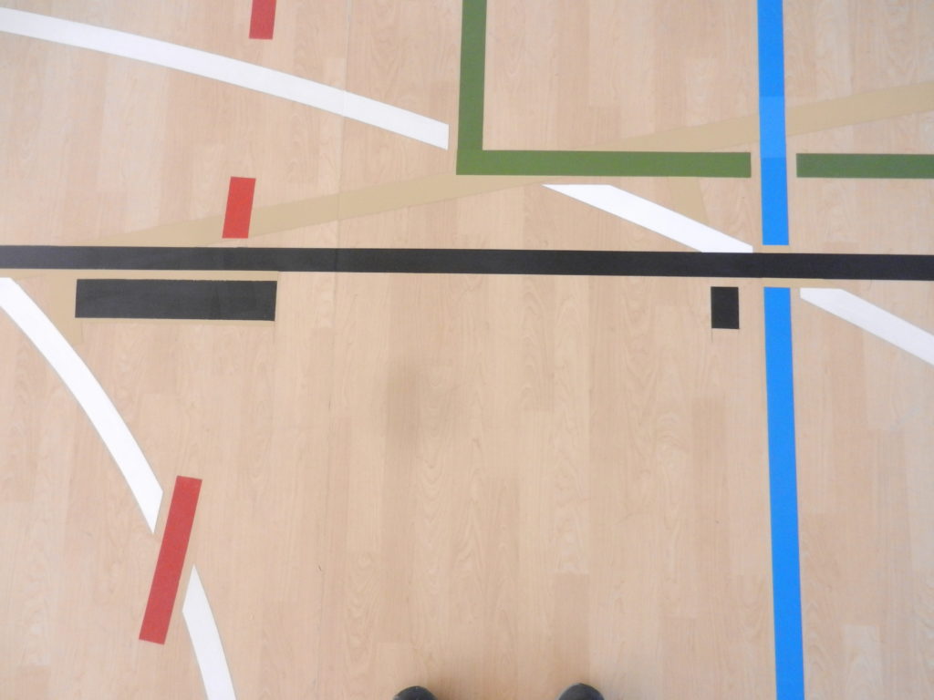 Croisement terminé sur un sol PVC décor bois, ligne de basket continue et prioritaire, autres lignes arrêtées à distance