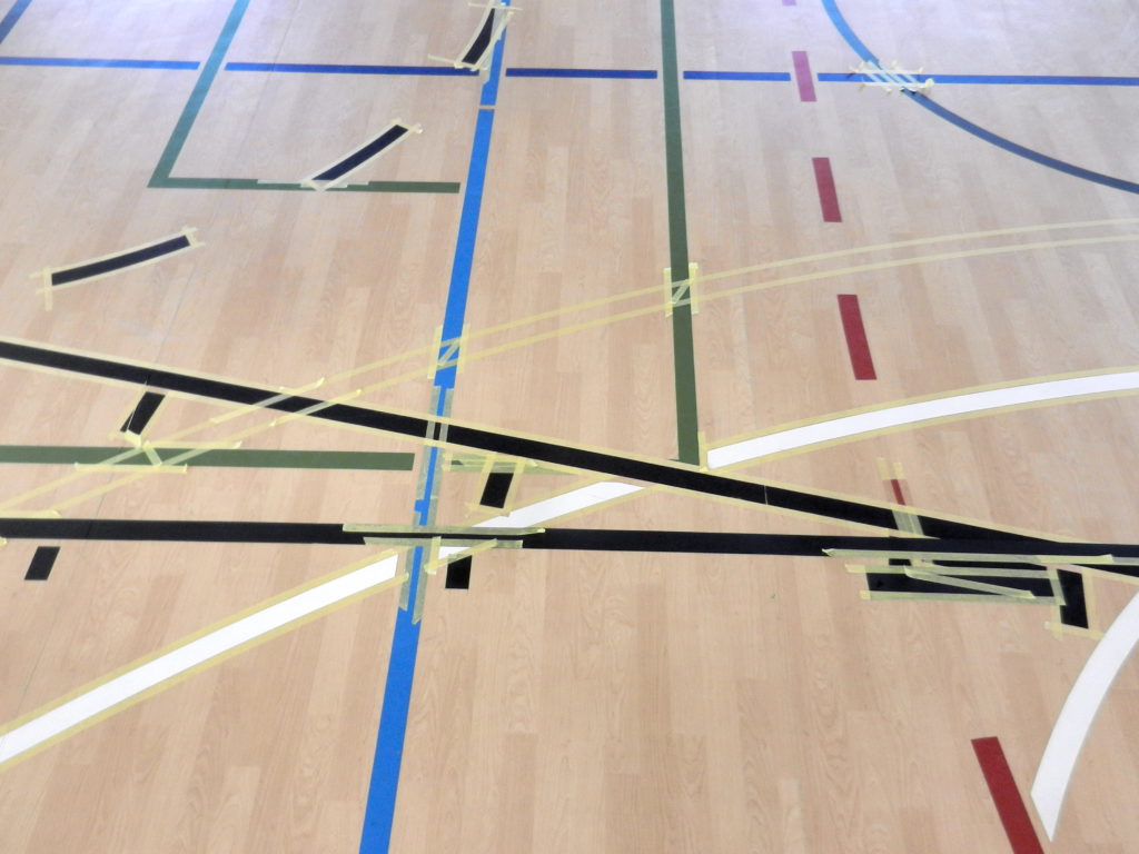 Croisements de lignes de jeu sur un sol PVC décor bois, nouvelles lignes de basket noires et rubans de masquage aux intersections