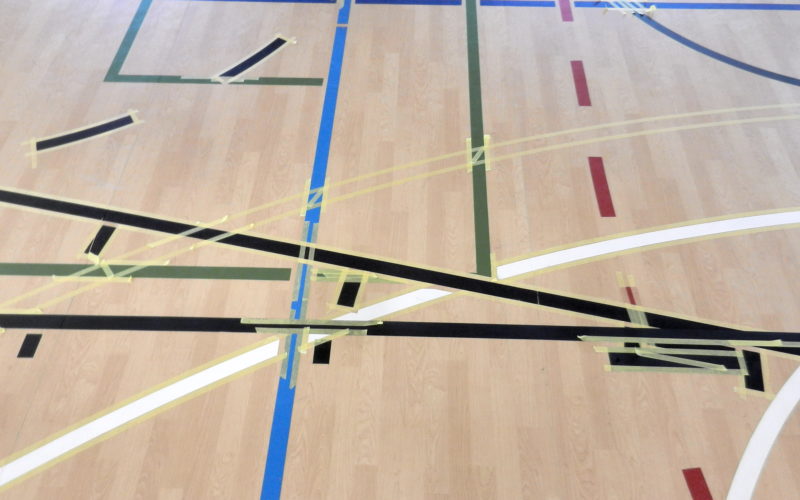 Croisements de lignes de jeu sur un sol PVC décor bois, nouvelles lignes de basket noires et rubans de masquage aux intersections