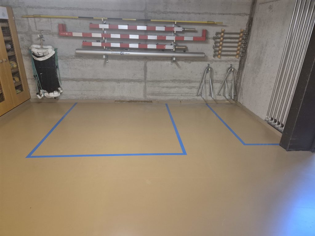 Emplacements délimités au sol sous le matériel de gymnastique rangé au mur