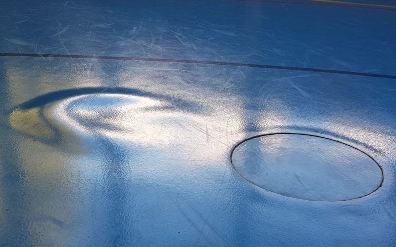 Très grosse cloque dans le revêtement d'un sol sportif, à côté d'un couvercle de douille, après un dégât d'eau passé inaperçu