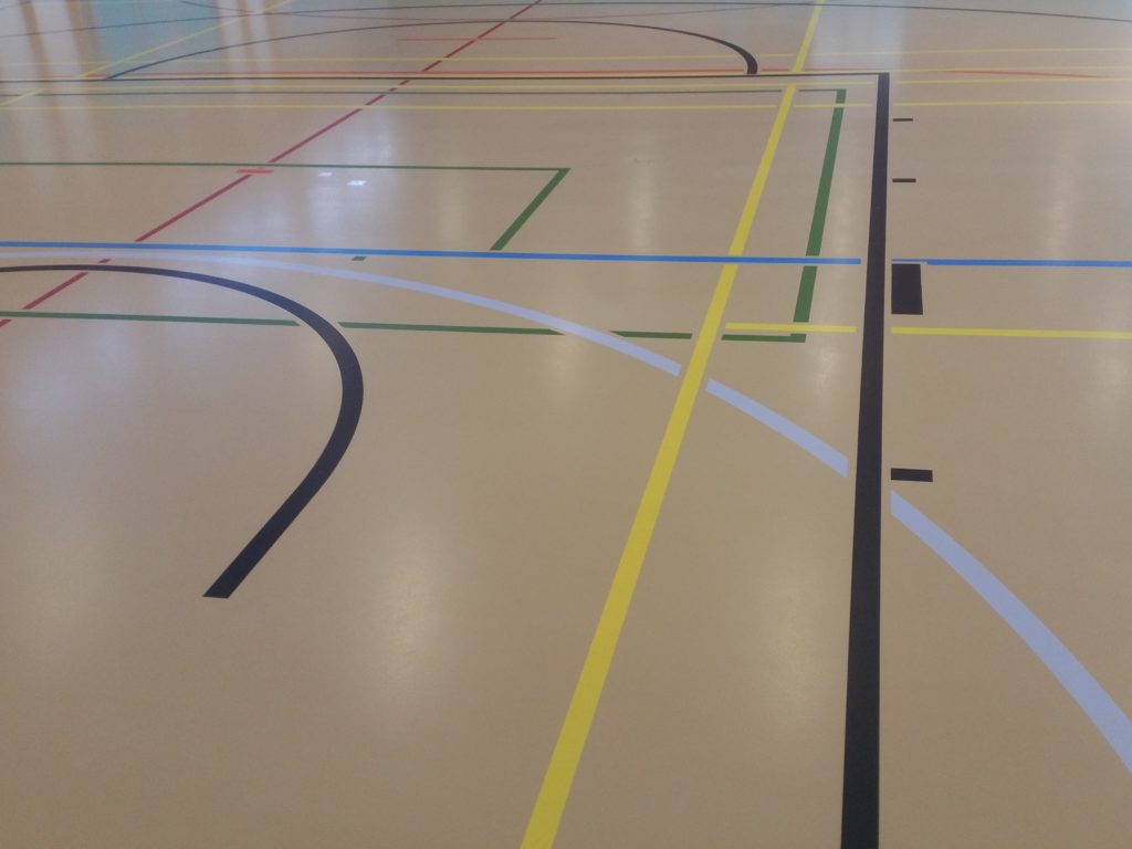 Gros plan du marquage terminé sur un sol sportif, lignes de jeu nettes de plusieurs couleurs