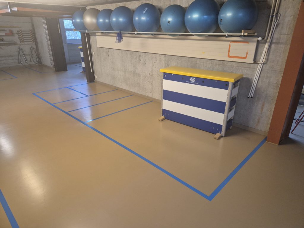 Zones de rangement marquées en bleu au sol d'un local à engins de gymnastique