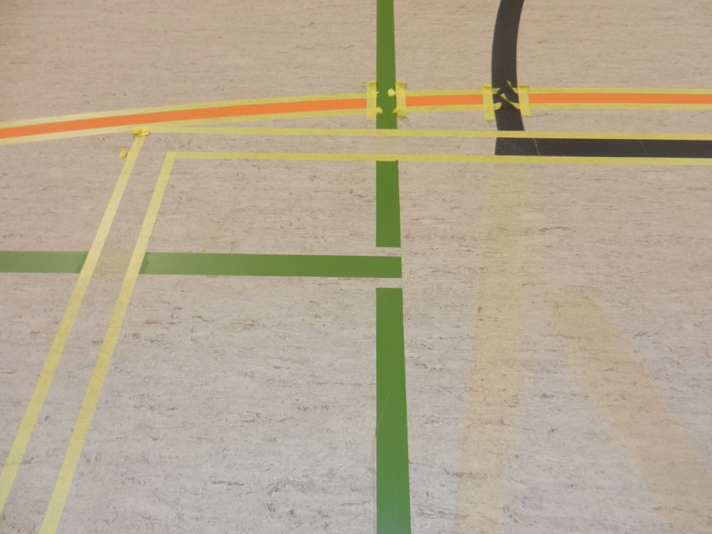 Ruban de marquage posé autour des nouvelles lignes de basket sur un sol sportif en linoléum