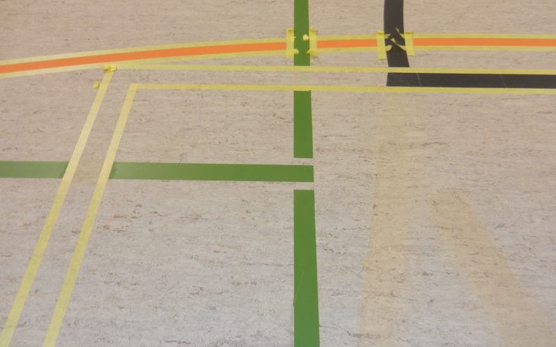 Ruban de marquage posé autour des nouvelles lignes de basket sur un sol sportif en linoléum