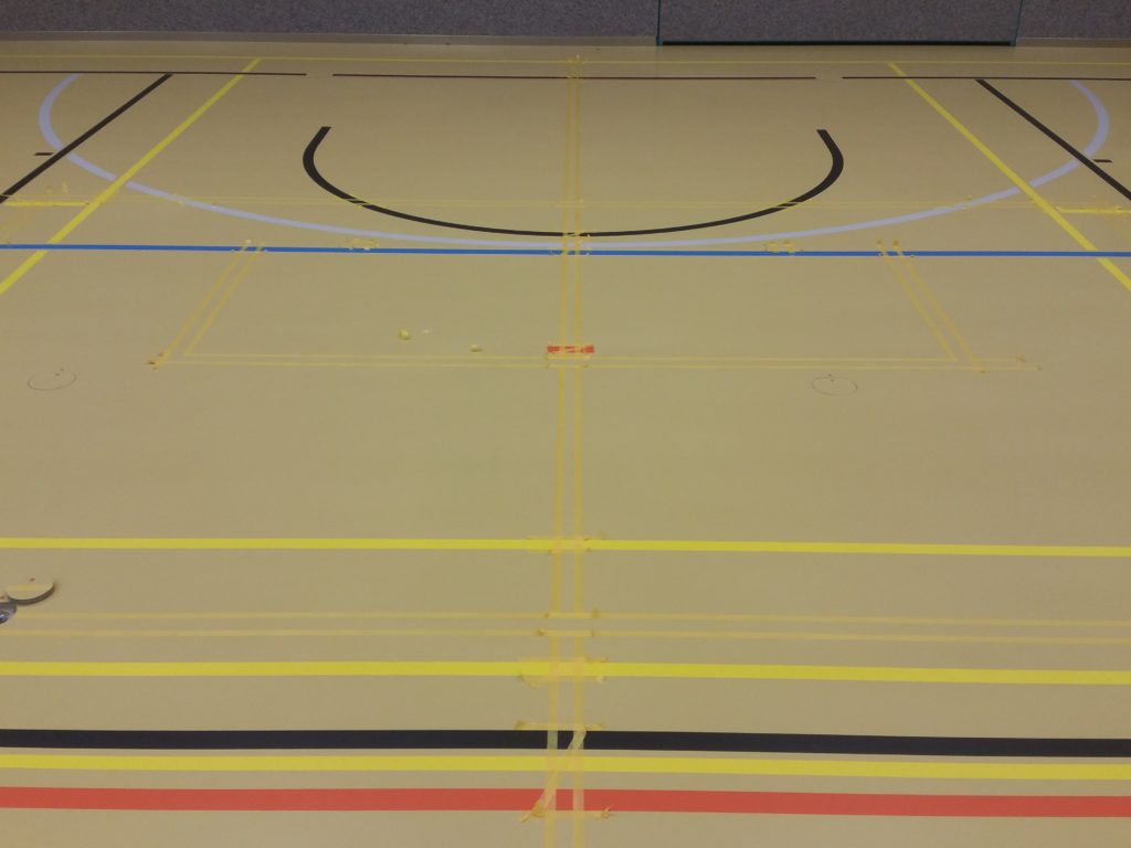 Marquage des nouvelles lignes de jeu dans une salle de sport, par-dessus le marquage existant