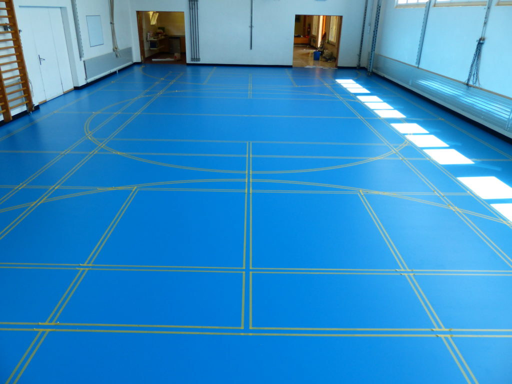 Lignes de jeu délimitées au scotch sur un sol sportif en résine bleu ciel
