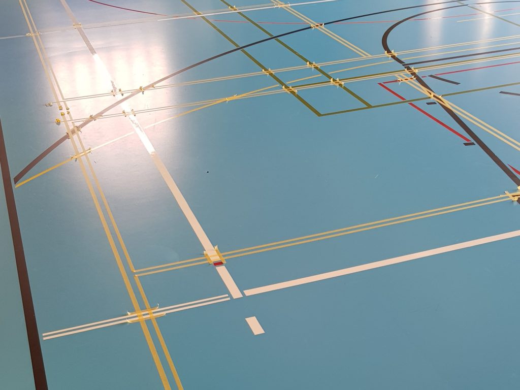 Nouveaux terrains de badminton marqués en doubles rubans sur un sol sportif, prêts pour la peinture