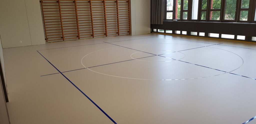 Salle de rythmique avec un sol sportif en résine, rectangle et croix en bleu et deux cercles blancs