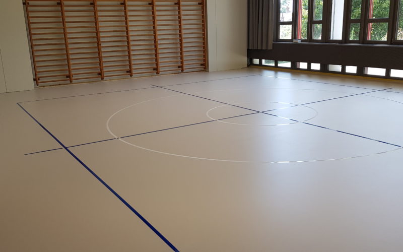 Salle de rythmique avec un sol sportif en résine, rectangle et croix en bleu et deux cercles blancs