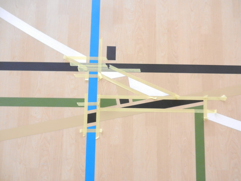 Croisement de lignes sur un sol PVC décor chêne, ancienne ligne masquée en beige et espaces réservés au ruban