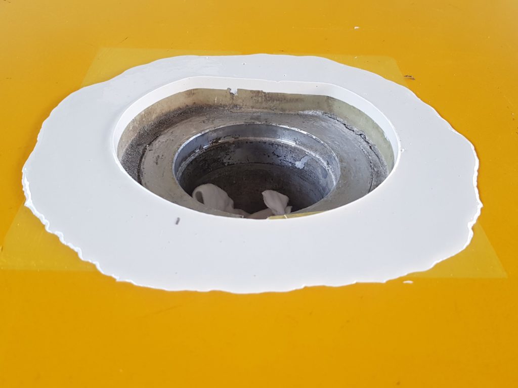 Nouveau pourtour en résine polyuréthane coulé autour d'une douille de sol sportif, avant la mise en peinture