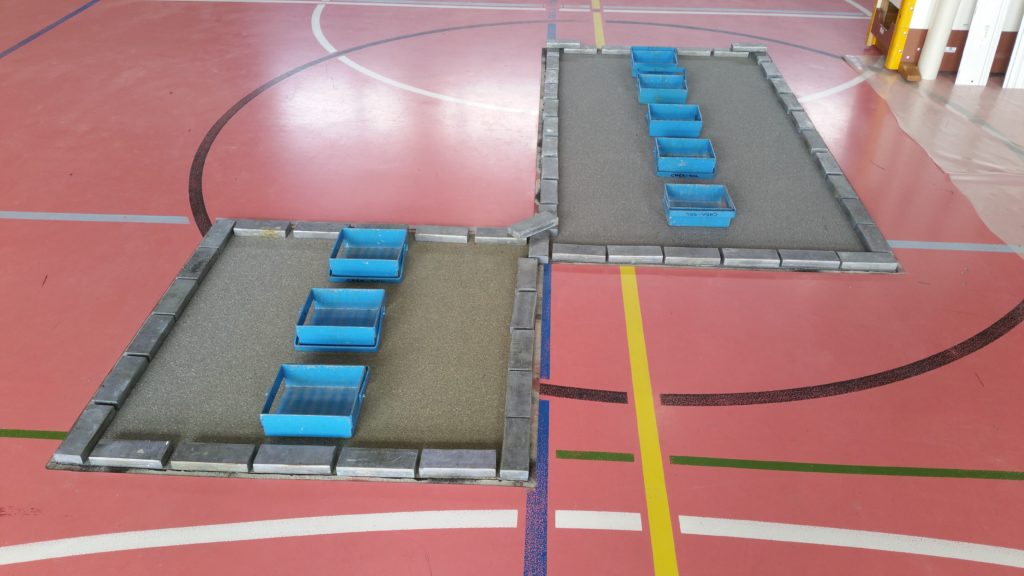 Deux zones refaites au centre d'un terrain de sport, nouvelle sous-couche collée et lestée par des lingots de plomb pendant le séchage