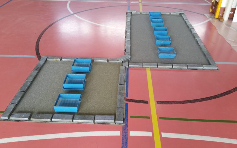 Deux zones refaites au centre d'un terrain de sport, nouvelle sous-couche collée et lestée par des lingots de plomb pendant le séchage