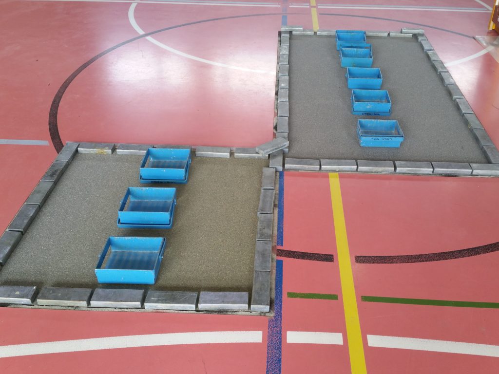 Deux zones refaites au centre d'un terrain de sport, nouvelle sous-couche collée et lestée par des lingots de plomb pendant le séchage