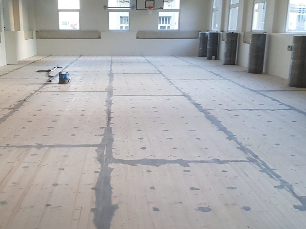 Panneaux trois plis en sapin posés sur le plancher d'origine comme support du sol sportif