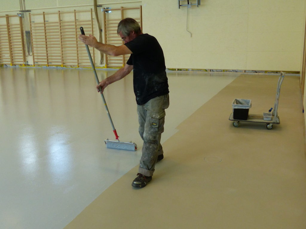 Application au rouleau de la peinture de sol gris clair sur la résine polyuréthane