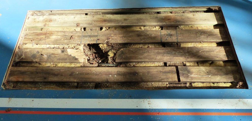 Sol sportif ouvert le long d'un mur, plancher pourri et lambourdes noircies par une fuite d'eau derrière le galandage