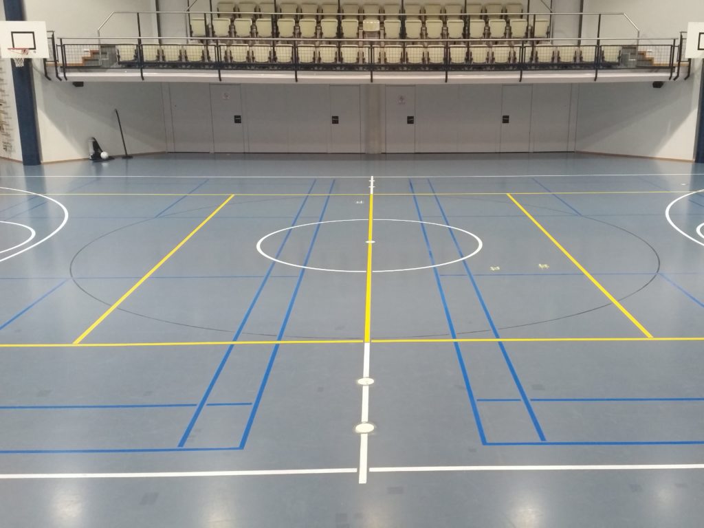 Vue d'ensemble d'une salle de sport avec quatre terrains de badminton remarqués en bleu ciel