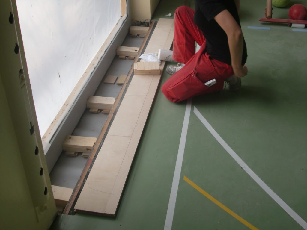 Pose de lambourdes calées et de panneaux de plancher pour raccorder un sol sportif à un nouveau vitrage