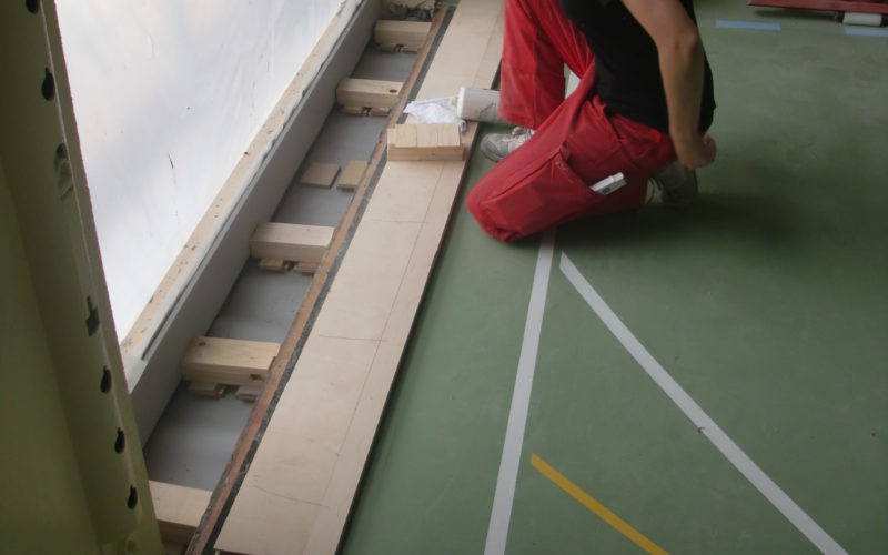 Pose de lambourdes calées et de panneaux de plancher pour raccorder un sol sportif à un nouveau vitrage