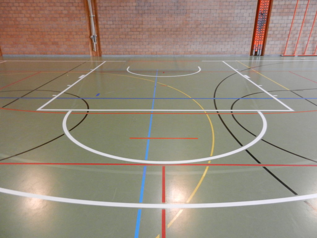 Raquette et zone de non-charge de basket tracées en blanc sur un sol sportif vert