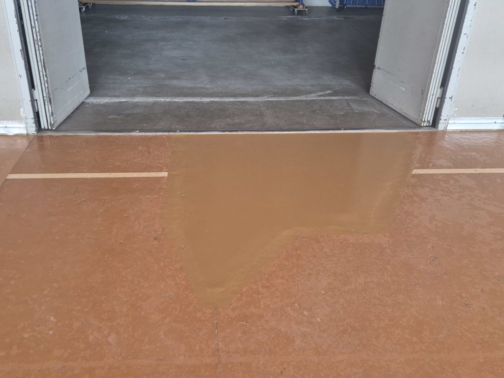 Zone réparée recouverte d'une peinture deux composants dans la teinte du lino-liège existant, devant un local à engins