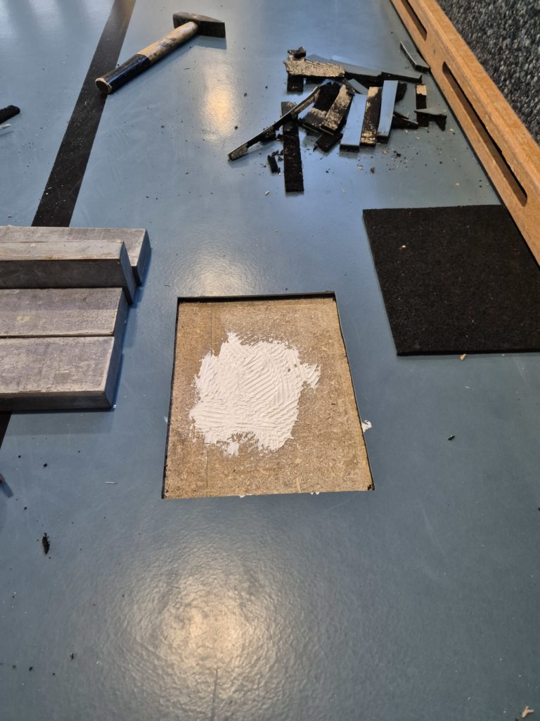 Zone découpée d'un sol sportif laissant apparaître le plancher en panneau, anciennes couches retirées et nouvelle sous-couche prête à la pose