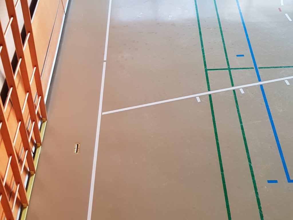 Sol de salle de gymnastique après le traitement de ses fissures, réparations discrètes entre les lignes de jeu