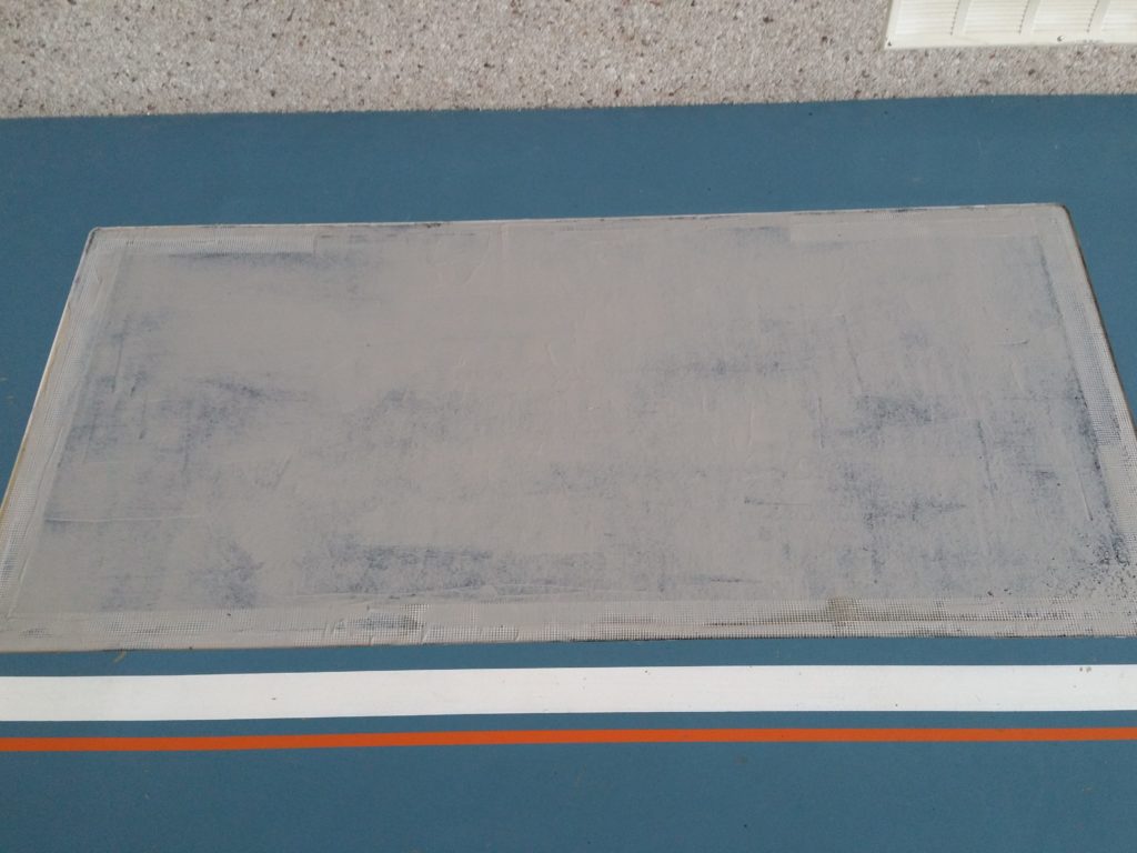Nouvelle couche de résine appliquée sur une zone reconstruite de sol sportif, treillis d'armature visible sur les bords