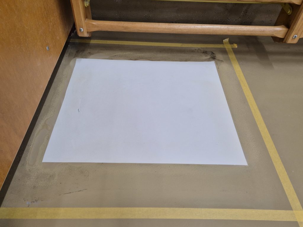 Résine polyuréthane durcie sur la zone réparée d'un sol sportif, surface délimitée par du ruban de masquage avant la peinture
