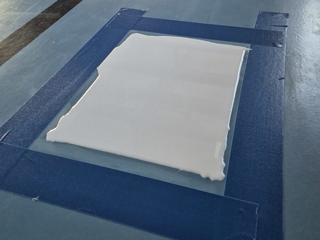 Résine polyuréthane fraîchement coulée dans la zone réparée d'un sol sportif, pourtour protégé par du ruban de masquage
