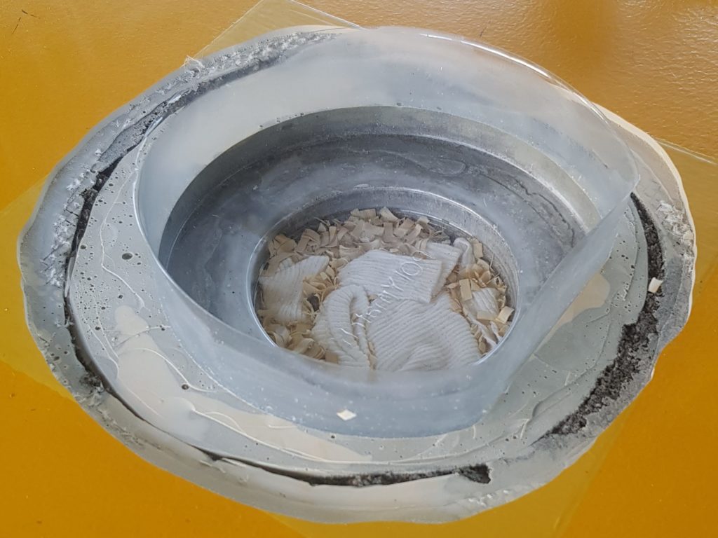 Résine fissurée retirée autour d'une douille métallique de sol sportif, moule transparent en place pour le nouveau pourtour