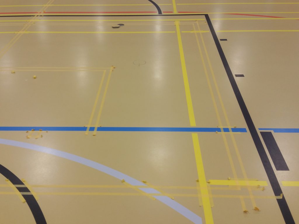 Gros plan du marquage de nouvelles lignes scolaires sur un sol sportif, doubles rubans le long du tracé existant