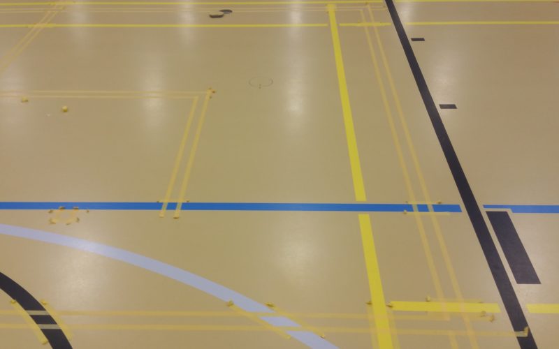 Gros plan du marquage de nouvelles lignes scolaires sur un sol sportif, doubles rubans le long du tracé existant