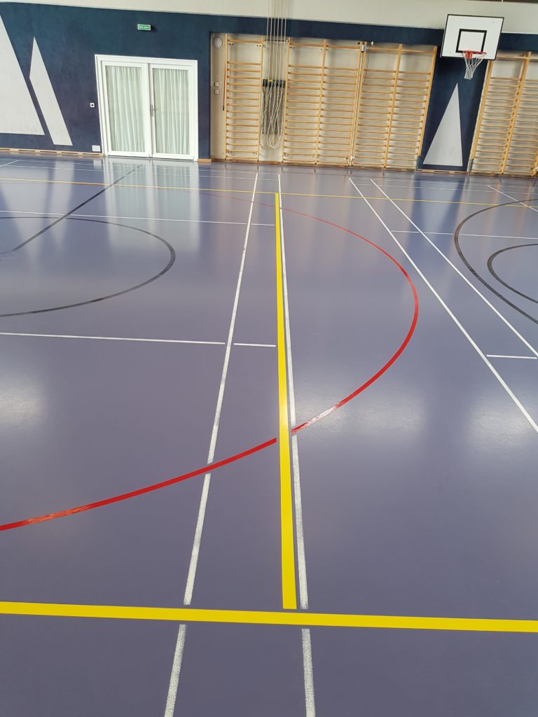 Salle de sport après remarquage, nouvelles lignes jaunes et rouges bien contrastées sur le sol bleu violet