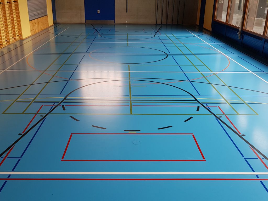 Salle polyvalente après remarquage, lignes de jeu nettes aux couleurs vives et nouveaux terrains de badminton