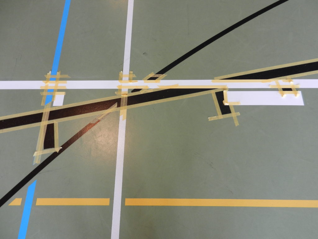 Scotch posé aux croisements de lignes pour le marquage d'un sol sportif
