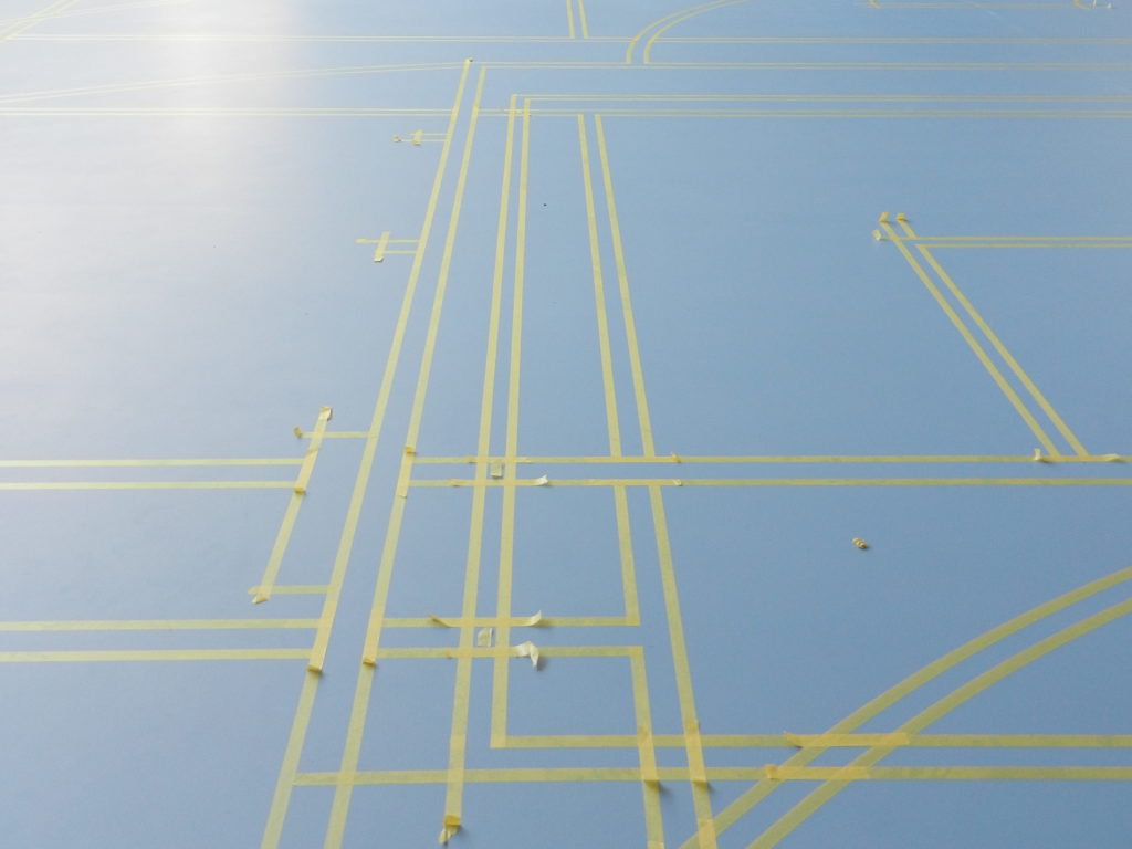 Lignes de jeu délimitées au scotch sur un sol sportif bleu avant la peinture des lignes